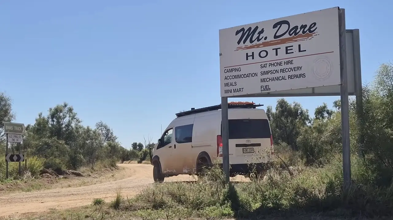 A white HiAce parked by the Mt Dare Hotel sign on a dirt track.